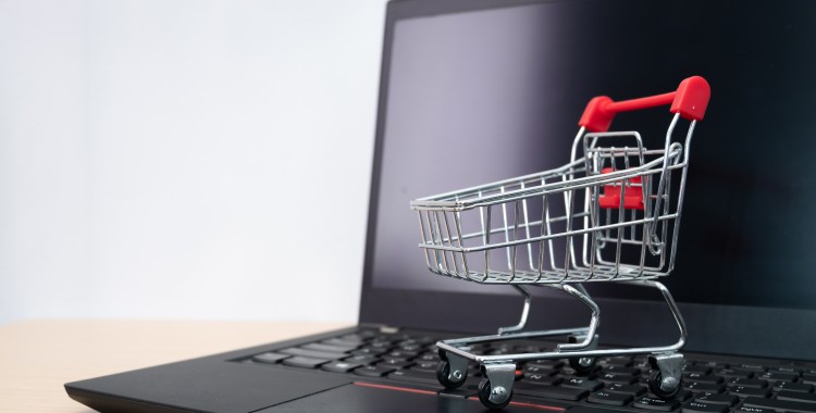 Carrito de la compra en miniatura sobre el teclado de un portátil