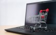 Carrito de la compra en miniatura sobre el teclado de un portátil